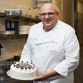 Konditormeister von Café Schmidt mit einer frisch gefertigten Schwarzwälder Kirschtorte
