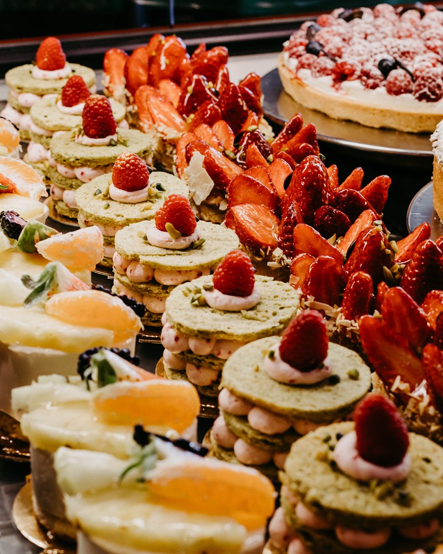 Kuchentheke im Café Schmidt mit Erdbeertörtchen, Pistazien-Törtchen und Käsekuchen